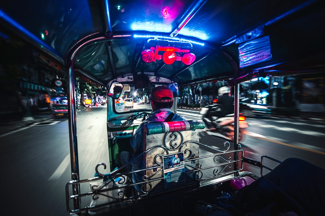 Colorful tuk-tuk interior at night with neon lights and driver in Bangkok traffic